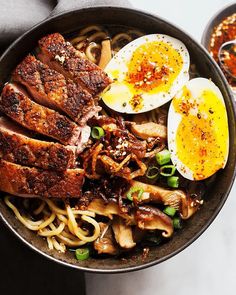 a bowl filled with meat, noodles and hard boiled eggs