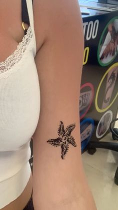 a woman's arm with a small black star tattoo on the left side of her arm