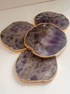 three pieces of purple marble sitting on top of a white counter next to each other