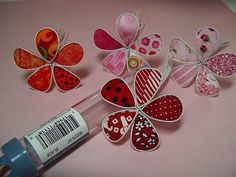 a bottle filled with lots of different types of paper flowers on top of a table