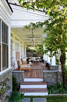 a porch with steps leading up to the front door and sitting area on either side