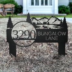 a metal sign sitting on top of a grass covered field next to a white house