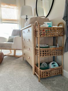 a baby changing table with baskets on it in a room next to a dresser and chair