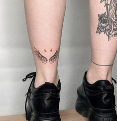 a woman's legs with tattoos and black shoes