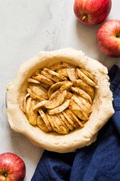 an apple pie sitting on top of a table next to two apples