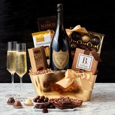 a wine gift basket with champagne, chocolates and crackers on a marble table