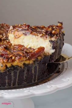 a chocolate cake with pecans and caramel toppings on a white platter