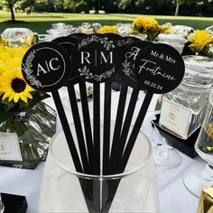 a table topped with lots of black and white tablesettis filled with yellow flowers