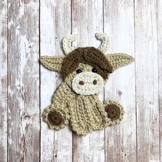 a crocheted cow laying on top of a wooden floor