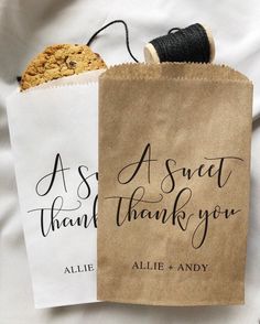 two brown paper bags with thank you and a cookie in them on a white sheet