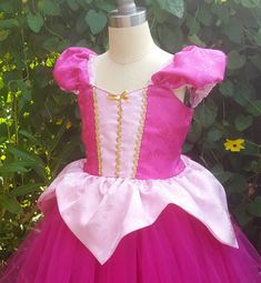 a pink and white princess dress on a mannequin headdress in front of flowers