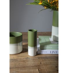 two green and white vases sitting next to each other on top of a wooden table