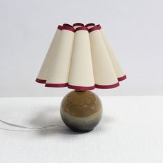 a lamp that is sitting on top of a white table cloth with a red ribbon around it