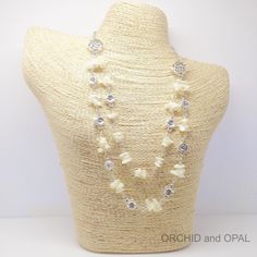 a white necklace with pearls and crystal stones on a mannequin headpiece for display