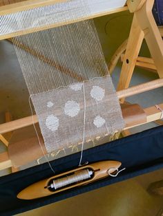 a weaving machine with a piece of cloth on it and a wooden spool next to it