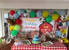 a birthday party with balloons, cake and farm animals on the table in front of it