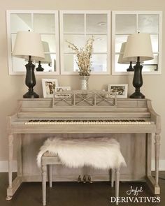 a white piano sitting in the middle of a living room next to lamps and pictures