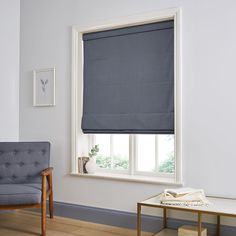 a living room with a chair and window covered in roman blind shades on the windowsill