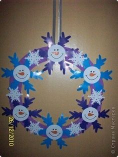 a paper wreath with snowmen hanging from it