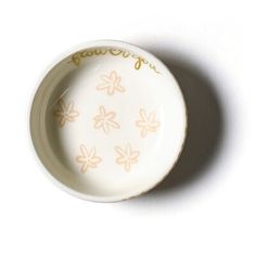 a small white bowl with flowers painted on the side and words written in gold ink