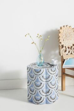 a small table with a vase on it next to a chair