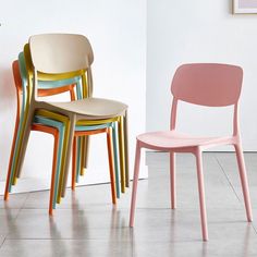 three different colored chairs sitting next to each other in front of a wall with a plant