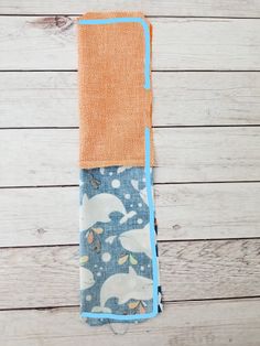 an orange and blue towel sitting on top of a wooden floor next to a white wall