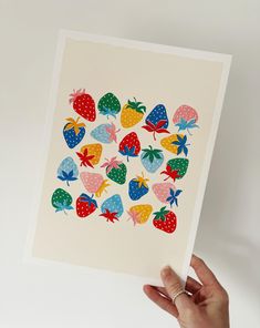 a person holding up a card with strawberries on it in front of a white background