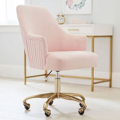 a pink office chair sitting on top of a wooden floor next to a white dresser