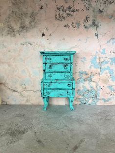 a blue dresser sitting in front of a wall