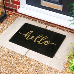 a black door mat with the word hello written in gold ink on it next to a front door