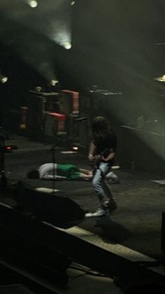 two people on stage with one person laying down and the other standing up in front of him