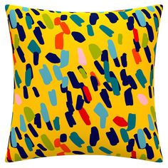 a yellow pillow with blue, green, and red shapes on it