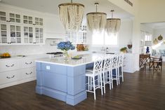 a kitchen with white cabinets and blue island