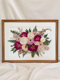 a floral arrangement in a gold frame on a white sheet