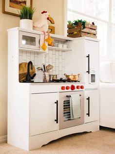 a white kitchen with an oven, microwave and counter top in front of a window