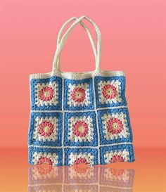 a crocheted bag sitting on top of a table next to a pink background