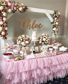 a table topped with lots of food and desserts next to a wall covered in flowers