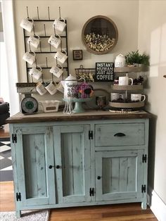 an old blue cabinet with coffee cups on top and other items sitting on the wall