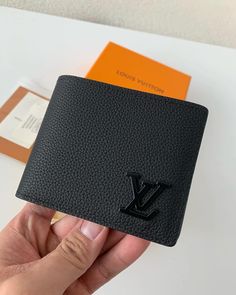 Embrace sleek sophistication with this minimalist wallet, inspired by the iconic Louis Vuitton design. Crafted from premium black leather with a subtle-grained texture, it exudes understated luxury. The signature LV emblem in a matching tonal finish adds a discreet touch of branding. Its slim profile and practical design make it a perfect everyday companion for the modern minimalist. Luxury Minimalist Wallets, Lv Wallet Mens, Black Formal Wallet With Embossed Logo, Black Business Wallets With Embossed Logo, Modern Textured Leather Wallet, Luxury Black Business Wallets, Luxury Black Wallet With Rfid Blocking, Modern Black Wallet With Smooth Grain, Designer Black Wallet With Embossed Logo