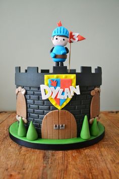 a cake that is decorated to look like a castle with a boy on top and a flag