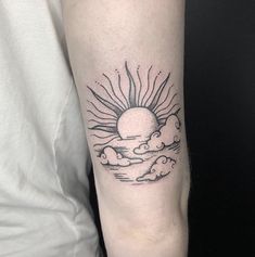 a sun and clouds tattoo on the left arm, with black ink in it's center