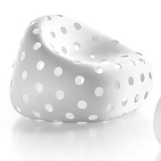 a white chair with polka dots on it next to a round object that is shaped like an egg