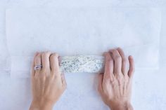 two hands holding a piece of cheese on a white surface