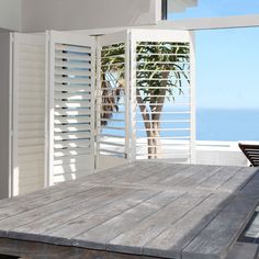 a wooden table sitting in front of a window with shutters on the outside side