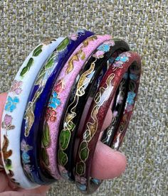 a hand holding five different colored bracelets