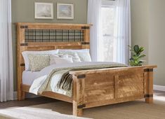 a wooden bed frame in a bedroom with two pictures on the wall and one window