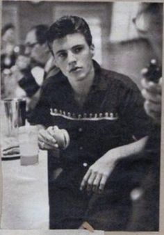 an old black and white photo of a man sitting at a table with a drink