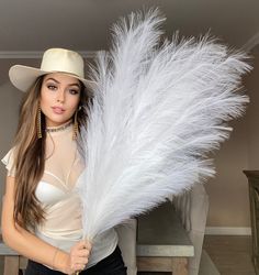 a woman wearing a cowboy hat and holding a white feather