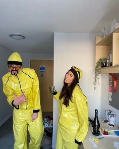 two people in yellow raincoats are standing next to each other and one is holding a beer